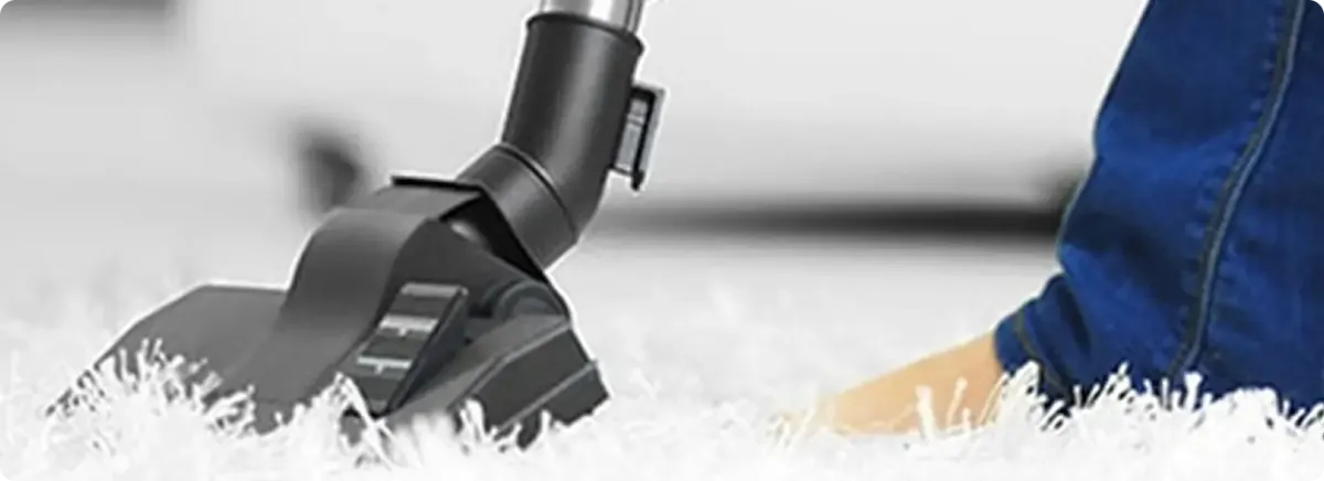 Close-up of a professional vacuuming a white carpet in Orange.